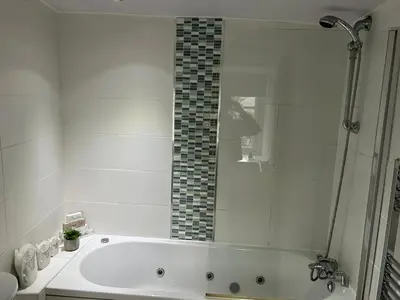 a white bathroom with a tub and a shower at Oronsay, 2 Weint End Cottages, Great Urswick, Ulverston Cumbria LA120SP in Moffat