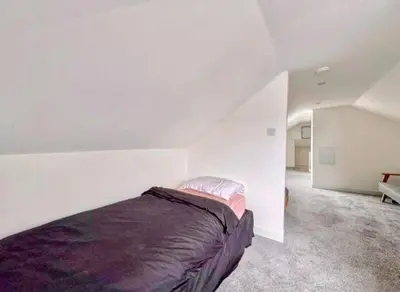 a bedroom with a bed in a white room at Central Charming Sea View Loft Flat in Troon