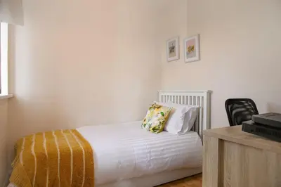 a bedroom with a white bed with a yellow blanket and a desk at 70 Abbotsbury Road, Bury St Edmunds, IP33 2HP in Moffat