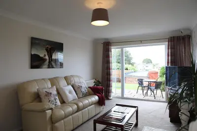a living room with a couch and a sliding glass door at 70 Abbotsbury Road, Bury St Edmunds, IP33 2HP in Moffat