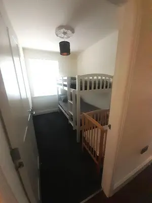 a room with a staircase with a crib and a window at Kirkcudbright Holiday Apartments - Apartment B in Kirkcudbright