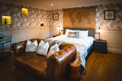 a bedroom with a bed and a leather couch at The Little Inn at Grasmere in Grasmere
