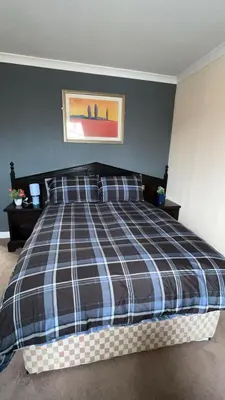 a bedroom with a large bed with a plaid blanket at QueensBerry Annan in Annan