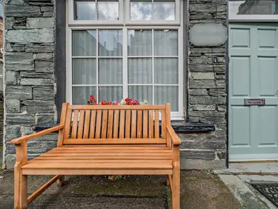 a wooden bench in front of a window with flowers at 1 Bed in Keswick 96314 in Keswick