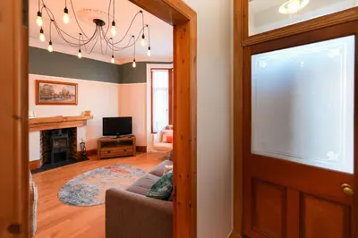 a living room with a couch and a chandelier at Seabreeze in Prestwick in Prestwick