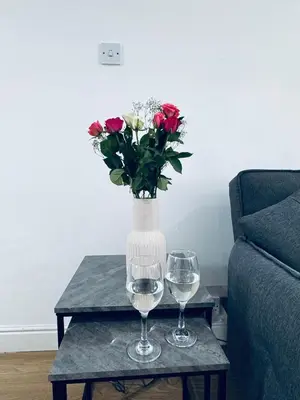 two wine glasses and a vase with flowers on a table at Holly Terrace - 2 Bedrooms - Sleeps 3 in Whitehaven