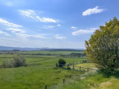 a green field with a fence on a hill at Townhead Mill in Dumfries