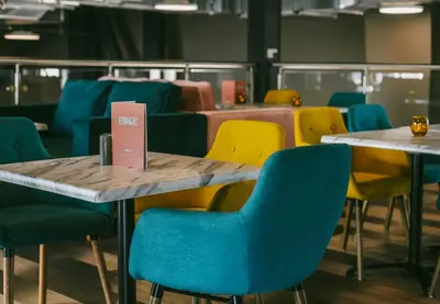a group of tables and chairs with blue chairs at The Edge in Whitehaven