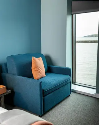 a blue chair with an orange pillow in a room at The Edge in Whitehaven