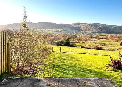 a field with a fence and mountains in the background at Lorton View, nestles on the fellside with walks from the door close to Lorton in Lorton