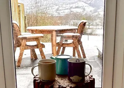 a window with two cups and a table in the snow at Lorton View, nestles on the fellside with walks from the door close to Lorton in Lorton