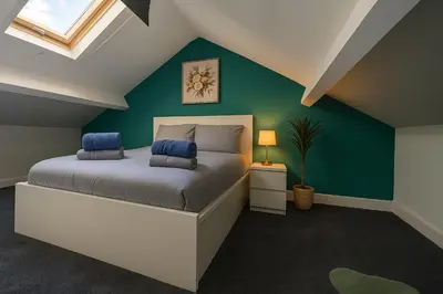 a bedroom with a bed with a green wall at Armstrong St - Cosy 3 Bedroom Home in Workington