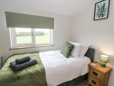 a small bedroom with a bed and a window at Daisy Cottage in Wigton