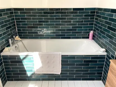 a blue tiled bathroom with a bath tub with towels at The Cart Barn in Moffat