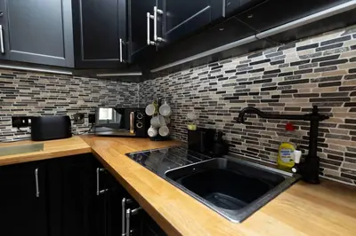 a kitchen with a sink and a brick wall at Troon - Coastal Getaway in Troon