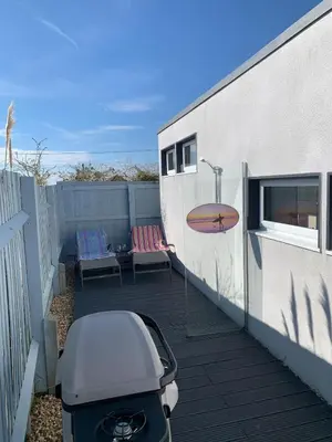 a patio with chairs and a surfboard on the side of a building at The Beach House in Moffat