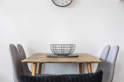 a table with chairs and a clock on the wall at Weaver Suite - Donnini Apartments in Ayr
