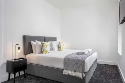a white bedroom with a large bed with yellow pillows at Weaver Suite - Donnini Apartments in Ayr