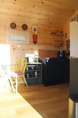 a kitchen with a stove and a yellow chair at Burnside of Ae Glamping Shepherd's Hut in Dumfries