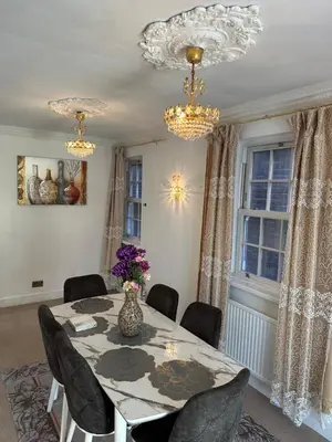 a dining room with a table and chairs and chandeliers at Fairholme Gardens House in Moffat