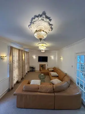a living room with a large couch and a chandelier at Fairholme Gardens House in Moffat