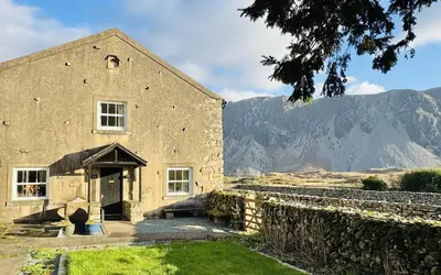a large stone building with mountains in the background at The Screes Apartment - Short stroll from Wastwater - Herdwick Cottages