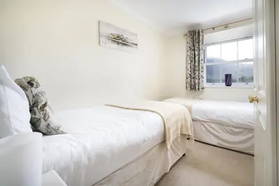 a white bedroom with two beds and a window at The Screes Apartment - Short stroll from Wastwater - Herdwick Cottages