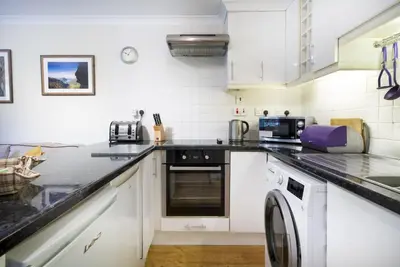 a kitchen with white cabinets and a dishwasher at The Screes Apartment - Short stroll from Wastwater - Herdwick Cottages