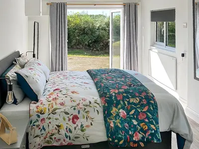 a bed with a flowered blanket on it with a window at Revita in Egremont