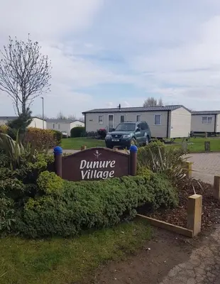 a sign for a university village in a yard at A&L Holiday Home Craigtara in Ayr