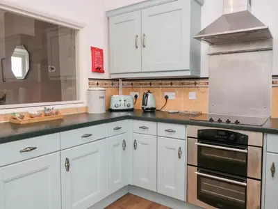 a kitchen with white cabinets and a stove top oven at Cosy Cottage in Cumbria, West of Lake District in Broughton Moor
