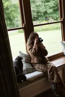 a woman sitting on a window sill taking a picture at The Coach House in Castle Douglas
