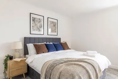 a bedroom with a large bed with blue pillows at Fabulous 1 Bed Harbour-side Apartment with Balcony in Whitehaven