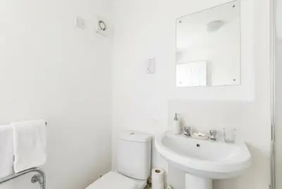 a white bathroom with a sink and a toilet at Fabulous 1 Bed Harbour-side Apartment with Balcony in Whitehaven