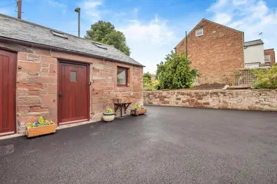 a brick building with a red door and a garage at 1 Bed in Wetheral oc-g32934 in Wreay