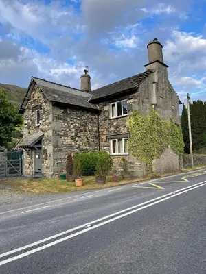 an old stone house on the side of a road at School House in Patterdale