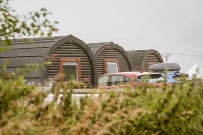 a row of wooden homes with a car parked in front at Unit 3 - High Pike View Camping Pod in Carlisle