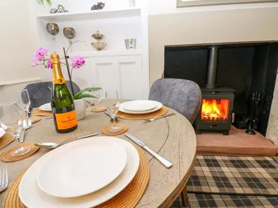 a table with plates and a bottle of wine and a fireplace at Milford in Carlisle