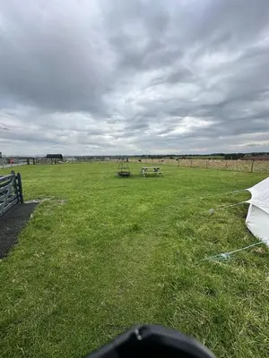 a field with a white umbrella in the grass at Unit 0 - Fully Serviced All Weather Pitch with Hot Tub in Carlisle