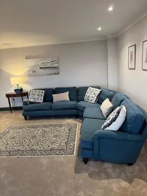 a living room with a blue couch and a rug at Rumblekirn in Annan