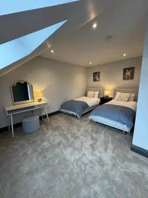 two beds in a room with a tv and a desk at Rumblekirn in Annan