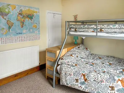 a bedroom with bunk beds and a map of the world at Miner's Rest in Frizington