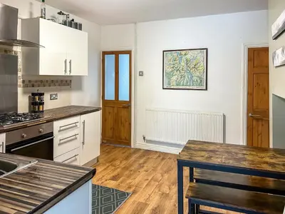 a kitchen with white cabinets and a wooden floor at Miner's Rest in Frizington