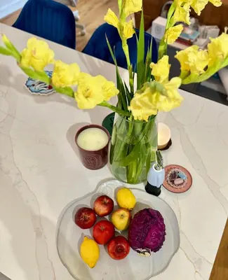 a table with a plate of fruit and a vase with flowers at Central London Designer Room with Balcony Elevator in Moffat