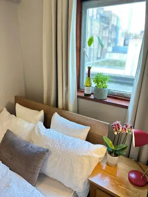 a bedroom with a bed with pillows and a window at Central London Designer Room with Balcony Elevator in Moffat