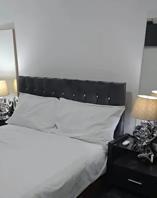 a bed with a black headboard and white pillows at Pazuri Apart in Moffat