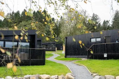 a house with a black fence and a walkway at Landal Barnsoul in Shawhead