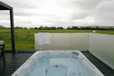 a bath tub on a deck with a view of a field at Landal Whitbarrow in Penruddock
