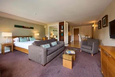 a bedroom with a bed and two chairs and a couch at Landal Whitbarrow in Penruddock