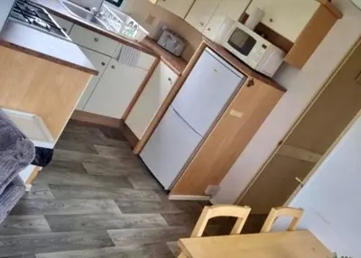 a small kitchen with a white refrigerator and a table at Loch View 28 in Stranraer